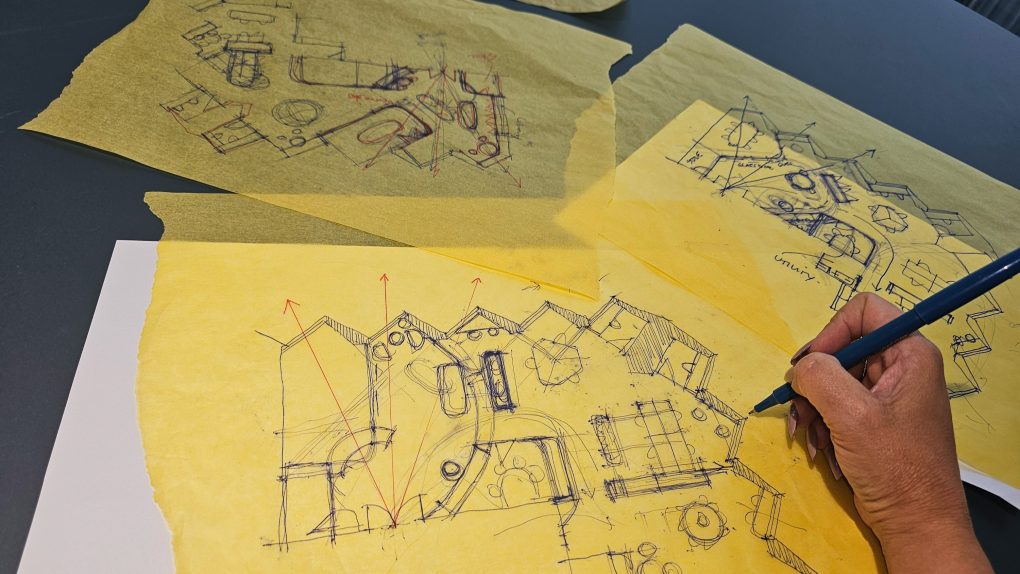 a designer sketches architectural drawings on yellow paper.